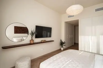 a white bedroom with a bed and a mirror at Seraya Residence 7 - 4BDR - Burj and DIFC skyline Views in Dubai