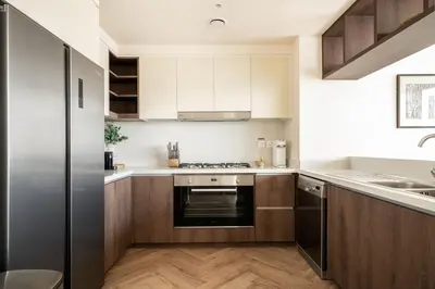 a kitchen with wooden cabinets and stainless steel appliances at Seraya Residence 9 - 4BDR - Skyline and Burj View - 3 Balconies in Dubai