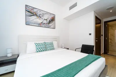 a bedroom with a white bed and a picture on the wall at New Contemporary Lux and Pool & Kids Amenities in JVC in Dubai