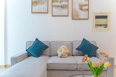 a couch with blue pillows and a stuffed animal on it at New Contemporary Lux and Pool & Kids Amenities in JVC in Dubai