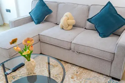 a living room with a couch and a glass table at New Contemporary Lux and Pool & Kids Amenities in JVC in Dubai
