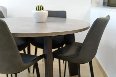 a table with black chairs and a white vase on it at New Contemporary Lux and Pool & Kids Amenities in JVC in Dubai