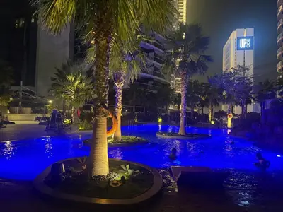 a pool with palm trees in a city at night at Royal Montania by DAMAC Paramount , Burj Khalifa View in Dubai