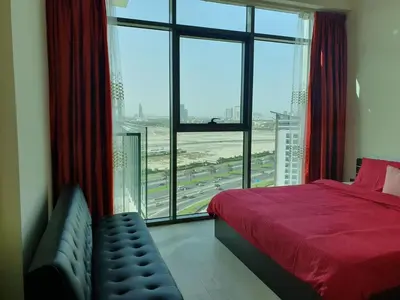a bedroom with a red bed and a large window at Dubai Skyline & Creek View - Homeyvillas in Dubai