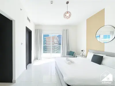 a white bedroom with a large bed and a large window at Luxury At AG Tower Business Bay & City Views in Dubai