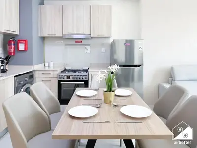 a kitchen with a wooden table and white chairs at Luxury At AG Tower Business Bay & City Views in Dubai