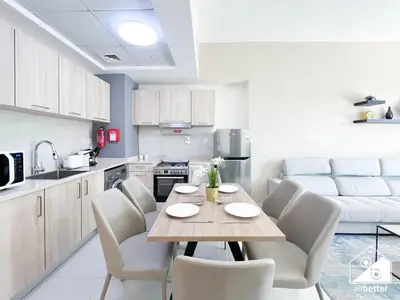 a kitchen with a wooden table and white chairs at Luxury At AG Tower Business Bay & City Views in Dubai