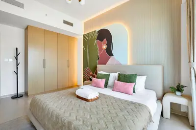 a bedroom with a large bed with pink and green pillows at Skyline Gem Full Burj View 2BR Suite with Dubai Mall access by Maxx Value homes in Dubai