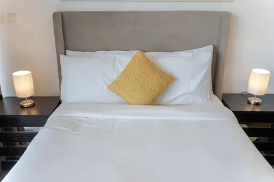 a bed with white sheets and a yellow pillow at Luxury Living in Matrix Tower Near Sports City in Dubai