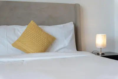 a white bed with a yellow pillow on it at Luxury Living in Matrix Tower Near Sports City in Dubai