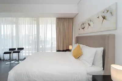 a bedroom with a large white bed and a desk at Luxury Living in Matrix Tower Near Sports City in Dubai