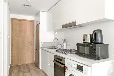 a white kitchen with a stove and a sink at Business Bay Studio Near Dubai Mall, Burj Khalifa & Downtown Hotspots in Dubai