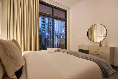 a bedroom with a bed and a large window at Designer Apartments in Kensington Waters, MBR City, with Pool Gym Sauna & Parking near Downtown and Creek in Dubai