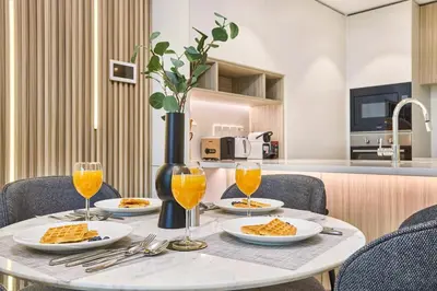 a table with plates of food and glasses of orange juice at Designer Apartments in Kensington Waters, MBR City, with Pool Gym Sauna & Parking near Downtown and Creek in Dubai