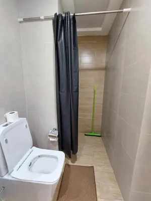 a bathroom with a toilet and a black shower curtain at Urban Studio - Walk to Metro - Homeyvillas in Dubai