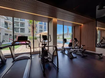 a gym with cardio equipment in a building with a large window at Luxurious Serenity 5-Star Lifestyle in JVC in Dubai
