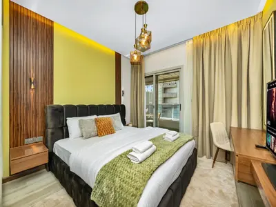 a bedroom with a large bed and a television at Stylish 1BHK Balcony with Canal View Near Shoba Metro Station in Dubai