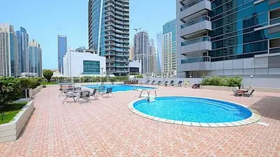 a swimming pool with tables and chairs in a city at Stylish 1BHK Balcony with Canal View Near Shoba Metro Station in Dubai