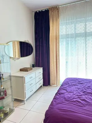 a bedroom with a purple bed and a dresser at Tranquil & Elegant Studio in Dubai Sports City in Dubai