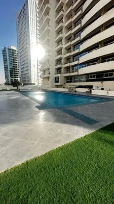 a large building with a swimming pool in front of it at Tranquil & Elegant Studio in Dubai Sports City in Dubai