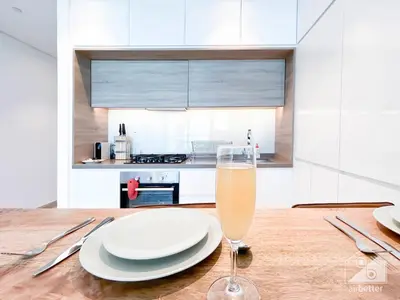 a glass of champagne sitting on a wooden table with plates at Balcony Bliss Cozy Studio with Marina Views in Dubai