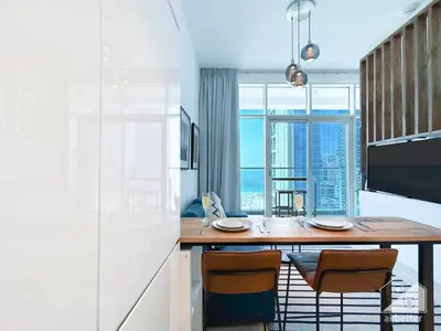 a kitchen with a table with chairs and a large window at Balcony Bliss Cozy Studio with Marina Views in Dubai