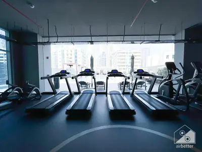 a gym with rows of treadmills and a large window at New! Cozy & Stylish Studio at Studio One Marina in Dubai