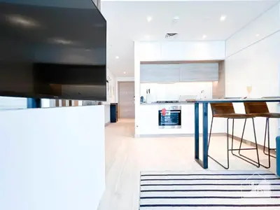 a kitchen with a blue table and a kitchen with white cabinets at New! Cozy & Stylish Studio at Studio One Marina in Dubai