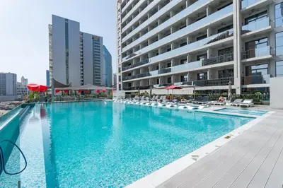 a swimming pool with chairs and a building at Vogue Downtown Mag318 near Burj Khalifa and Dubai Mall, Studio Apartment with Balcony, Canal and City View, Access to all Amenities in Sabkhah