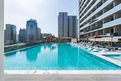 a large swimming pool with chairs and a building at Vogue Downtown Mag318 near Burj Khalifa and Dubai Mall, Studio Apartment with Balcony, Canal and City View, Access to all Amenities in Sabkhah
