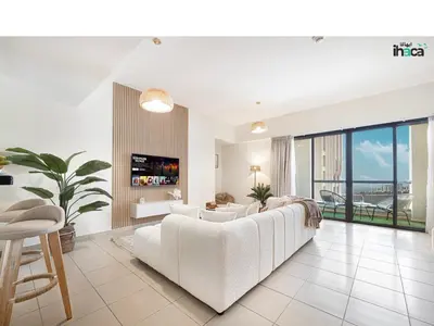 a living room with a white couch and a tv at Boho Studio Beachfront Ain Sea View JBR Walk 1min in Dubai