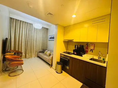 a kitchen with yellow cabinets and a living room at Burj Khalifa Skyline View in Dubai