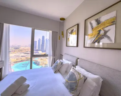 a bedroom with a white bed with a large window at GRANDE SIGNATURE with a direct Burj Khalifa view and Private Fountain Show at high floor with DXB AIRPORT VIP Shuttle option for 6 guests in Dubai
