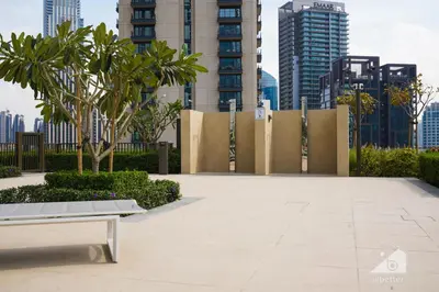 a park with a bench and palm trees and buildings at Burj Crown Luxury 2BR I Balcony & Panoramic Views in Dubai