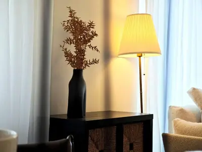 a vase with flowers on a table next to a lamp at FAM Living - 3BR Creekside Escape in Creek Rise Tower 2 in Dubai