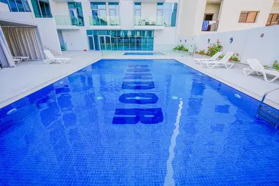 a large blue swimming pool with chairs in a building at Stylish Studio at Concord Concept, JVC in Dubai
