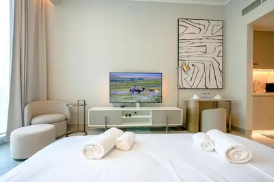 a bedroom with a white bed with a tv on it at Stylish Studio at Concord Concept, JVC in Dubai
