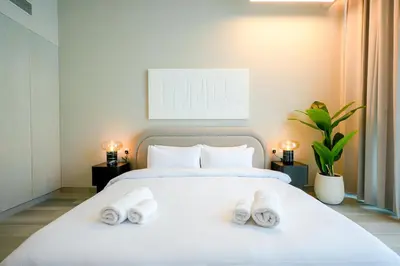 a bedroom with a white bed with two towels on it at Stylish Studio at Concord Concept, JVC in Dubai