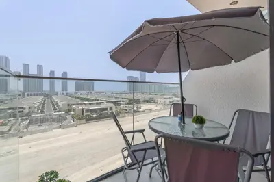 a table and chairs with an umbrella on a balcony at Chic and comfortable Studio Near Downtown and Canal in Dubai