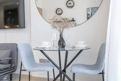a dining room table with chairs and a round mirror at Chic and comfortable Studio Near Downtown and Canal in Dubai