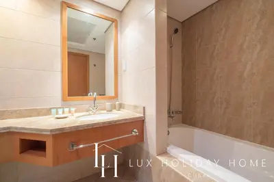 a bathroom with a sink and a tub and a mirror at LUX The Luxury Sunny JBR Beach Views 2 in Dubai