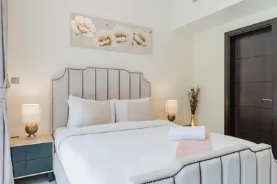 a bedroom with a large white bed and two lamps at RH- Elegant & Cozy 1BR , Prime Location , Walk to Metro Station in Dubai