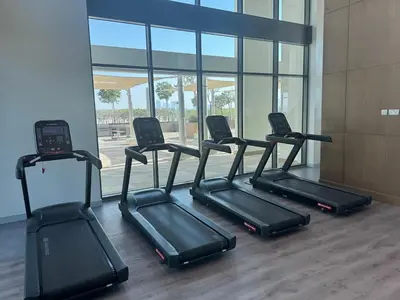 a row of treadmills in a gym with a window at Cosy studio Free Parking Free unlimited drinkable water Near Downtown in Dubai