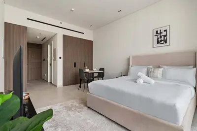 a bedroom with a large white bed and a table at Chic Studio in Arjan with Gym Pool Free parking in Dubai