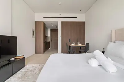 a bedroom with a large white bed and a table at Chic Studio in Arjan with Gym Pool Free parking in Dubai