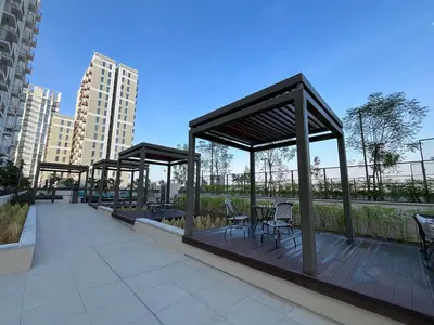 a covered deck with chairs and tables in a city at Chic 1BR in Socio Dubai Hills Near Park and Mall in Dubai