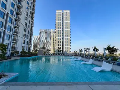 a large swimming pool in the middle of two tall buildings at Chic 1BR in Socio Dubai Hills Near Park and Mall in Dubai