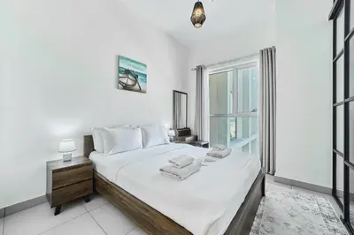 a white bedroom with a bed and a window at Chic 1BR in Socio Dubai Hills Near Park and Mall in Dubai
