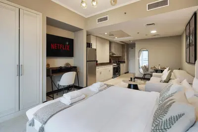 a bedroom with a white bed and a kitchen at Urban Studio Apartment in Goldcrest Views JLT in Dubai