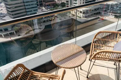a table and chairs on a balcony with a view of a city at Luxury JLT Studio Lake View Metro Pool Access in Dubai